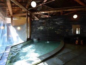 Ett spaområde med ett bubbelbad, träbjälkar och en stor spegel.