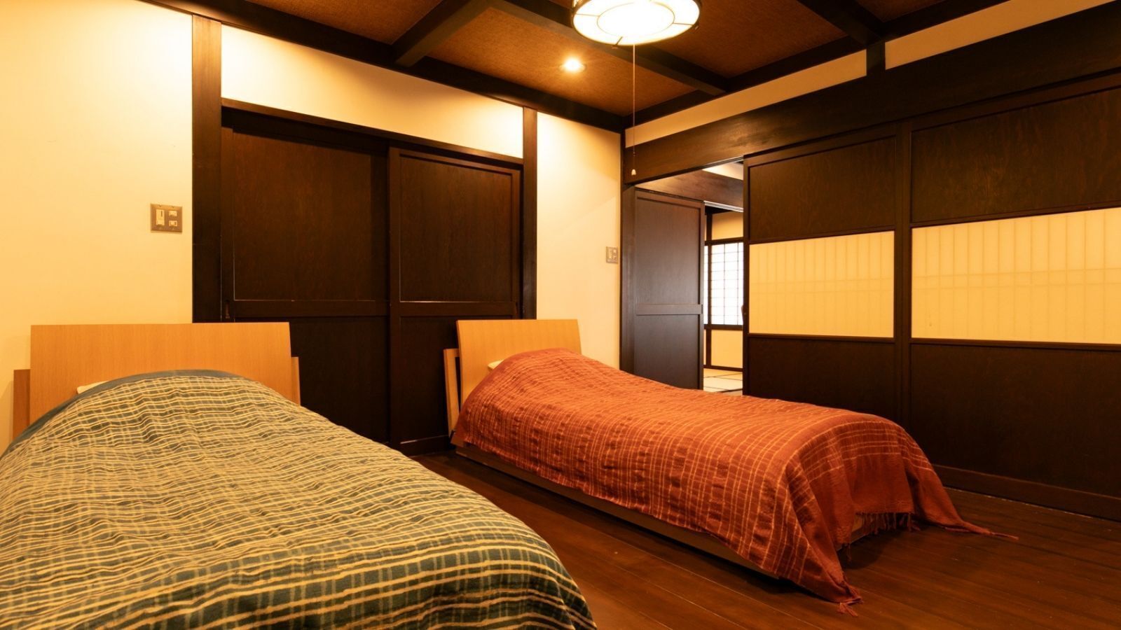 Een kamer met twee bedden, houten vloeren en schuifdeuren.