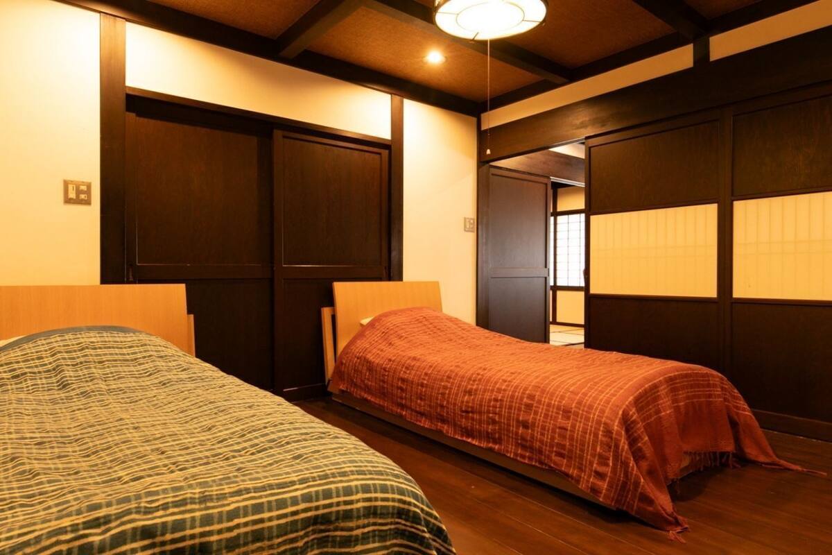 Une chambre avec deux lits, un plancher en bois et des portes coulissantes.
