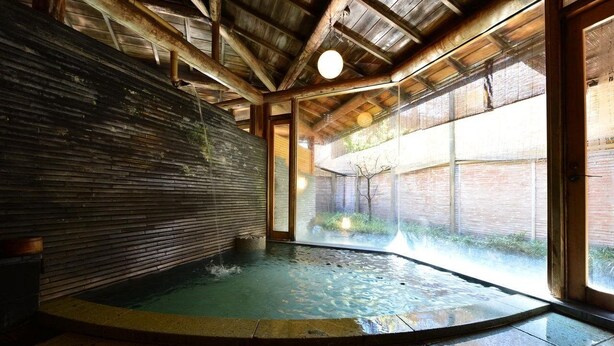 A hot tub area with a wooden ceiling and a glass wall. - Ryokan Sugimoto (Matsumoto)