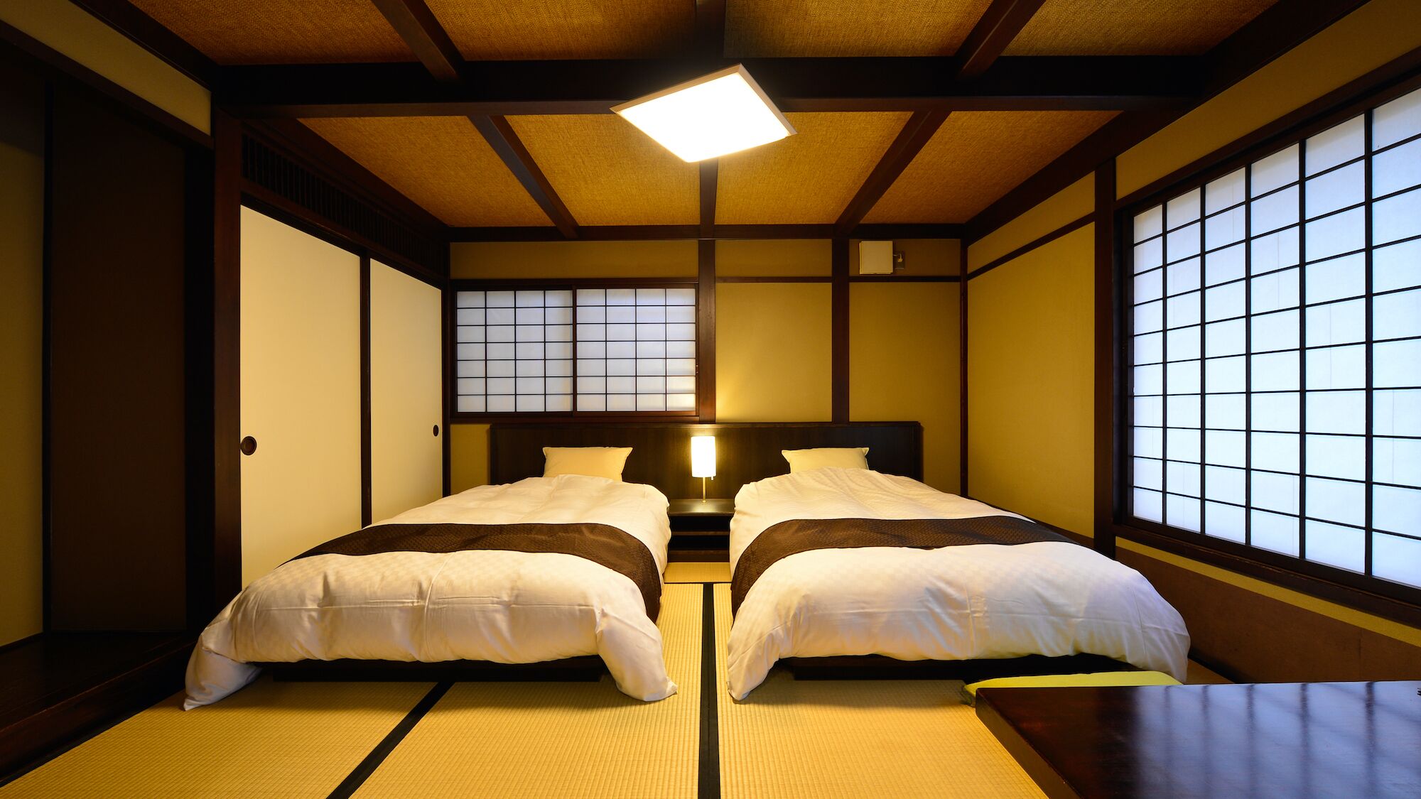 Een traditionele Japanse kamer met tatami vloerbedekking, een laag houten bed en shoji schermen.