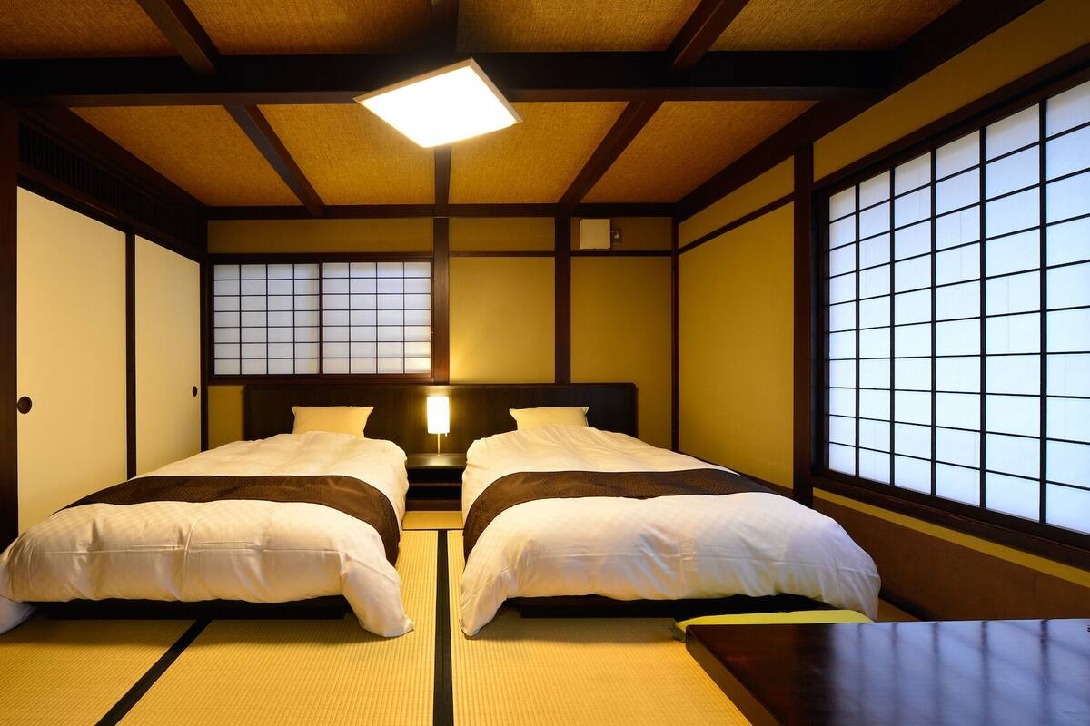 Une pièce de style japonais traditionnel, avec un sol recouvert de tatamis, un lit bas en bois et des paravents en papier de riz (shoji).