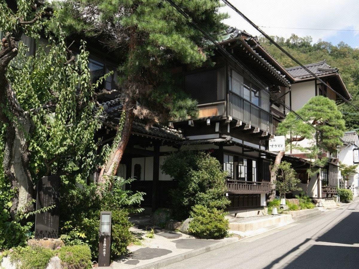 A traditional Japanese building with a wooden structure, a balcony, and a stone pathway leading to the entrance.