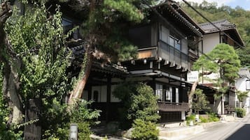 A traditional Japanese building with a wooden structure, a balcony, and a stone pathway leading to the entrance.