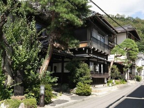A traditional Japanese building with a wooden structure, a balcony, and a stone pathway leading to the entrance.
