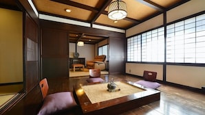 Ein traditioneller japanischer Raum mit Tatami-Bodenbelag, einem niedrigen Tisch mit Teeservice und verschiebbaren Türen.