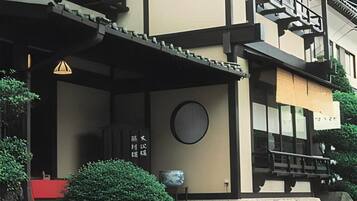 A building with a traditional architectural style, featuring a wooden staircase, a circular window, and a stone wall.