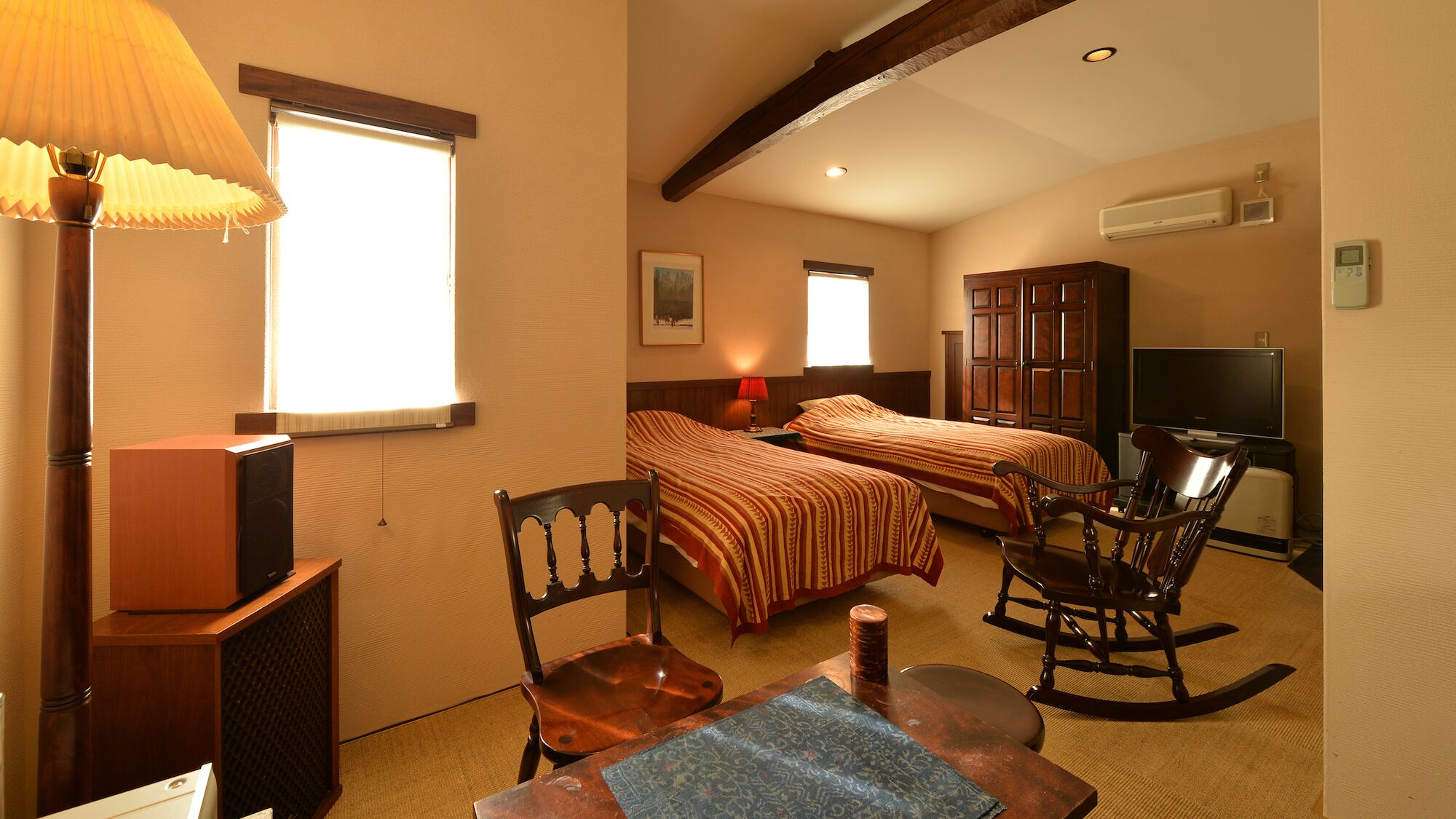 Een hotelkamer met twee bedden, een televisie, een bureau met stoel en een lamp.
