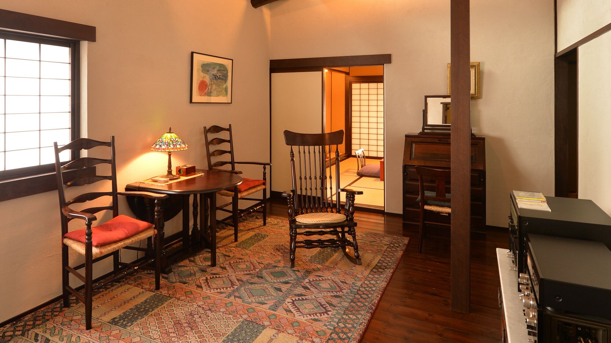 Een traditionele Japanse kamer met tatami vloerbedekking, een lage tafel, houten stoelen, een lamp en een piano.