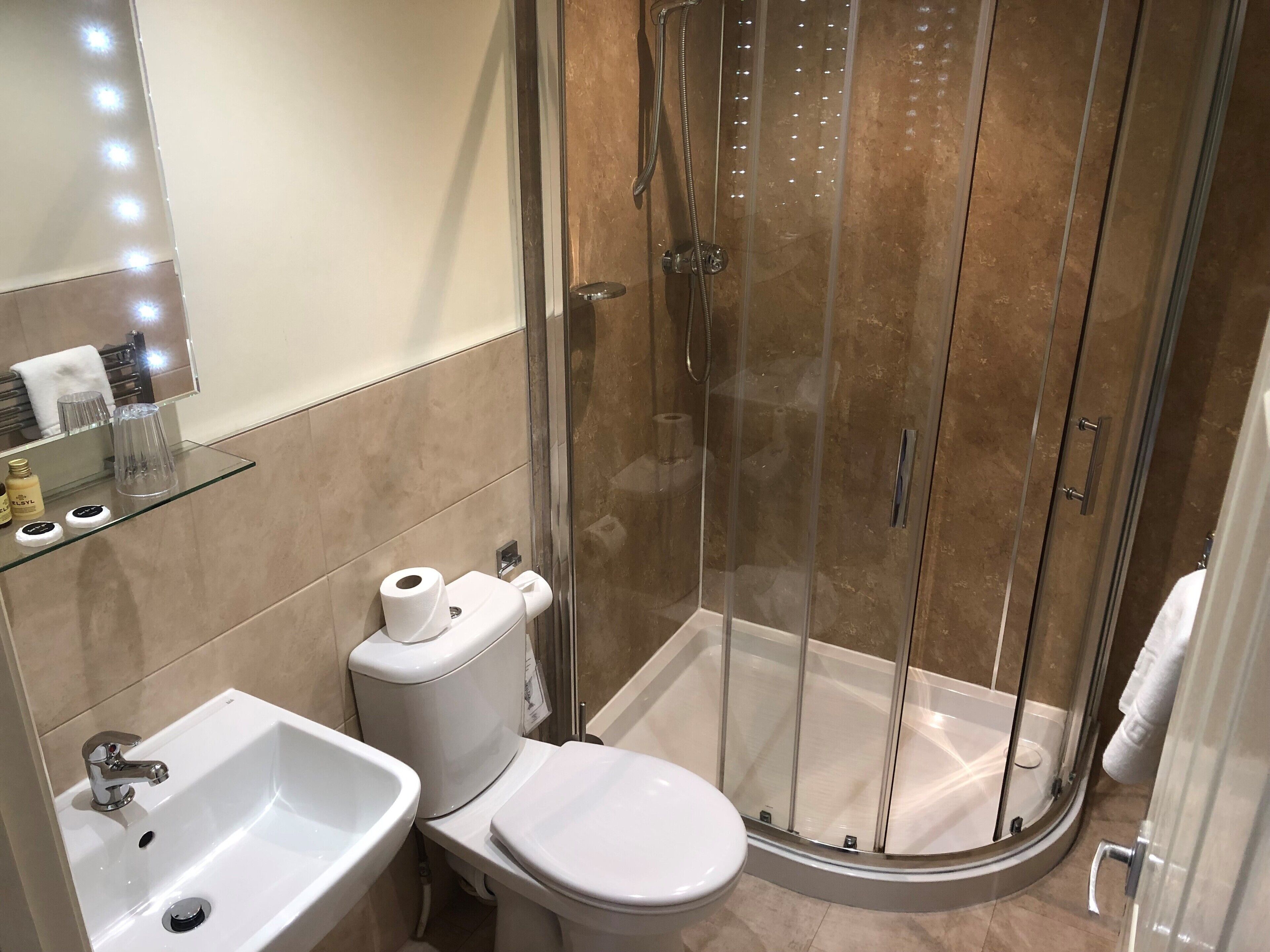 A modern bathroom with a glass-enclosed shower, a white sink, and a toilet.