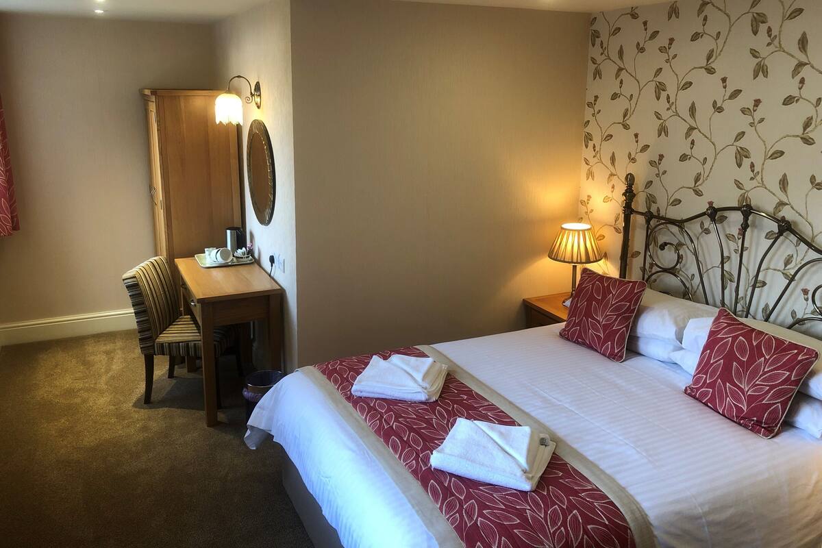 Une chambre d’hôtel avec un lit, un bureau et une chaise.