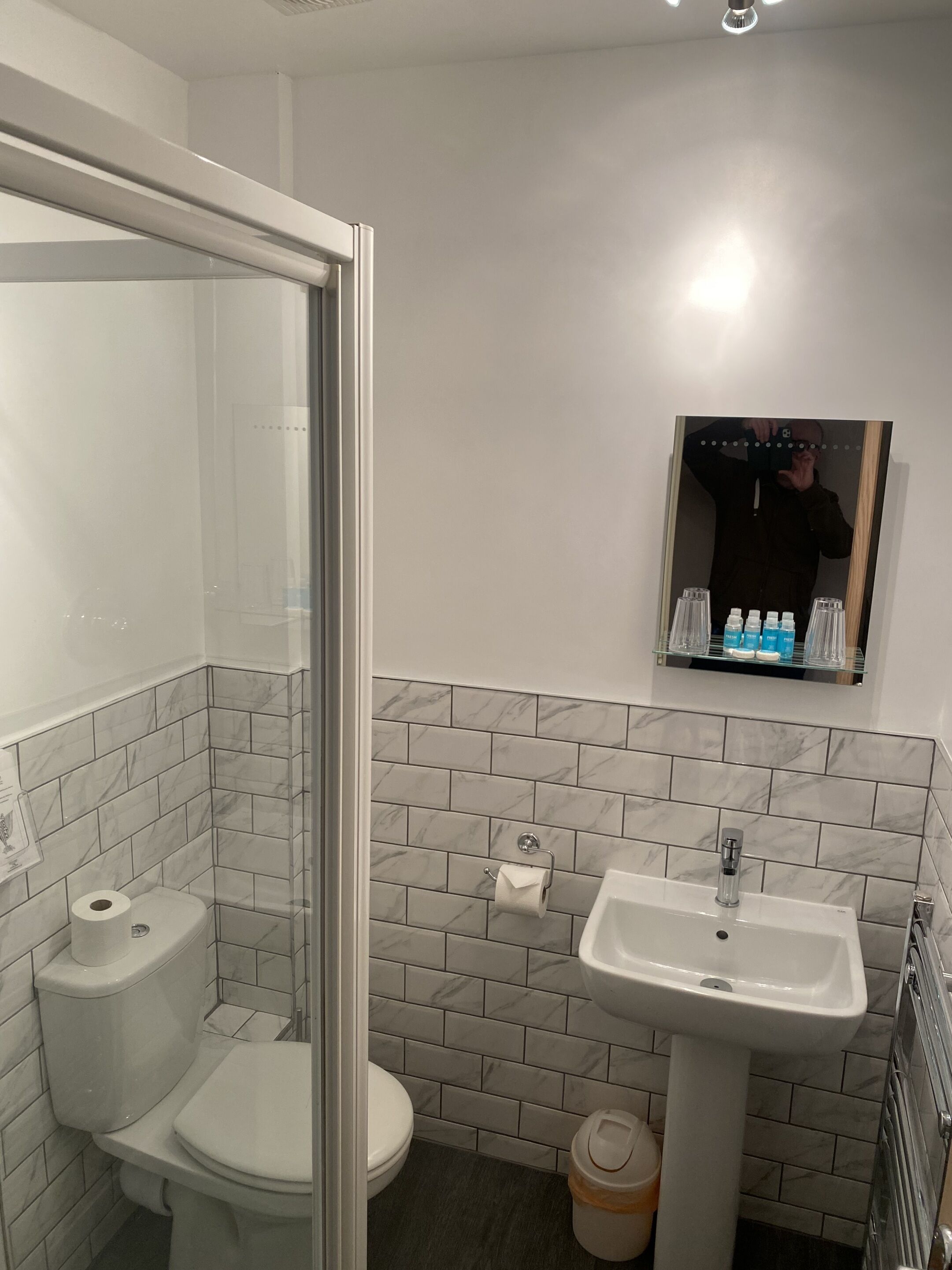 A bathroom with a toilet, sink, and a glass shower enclosure.