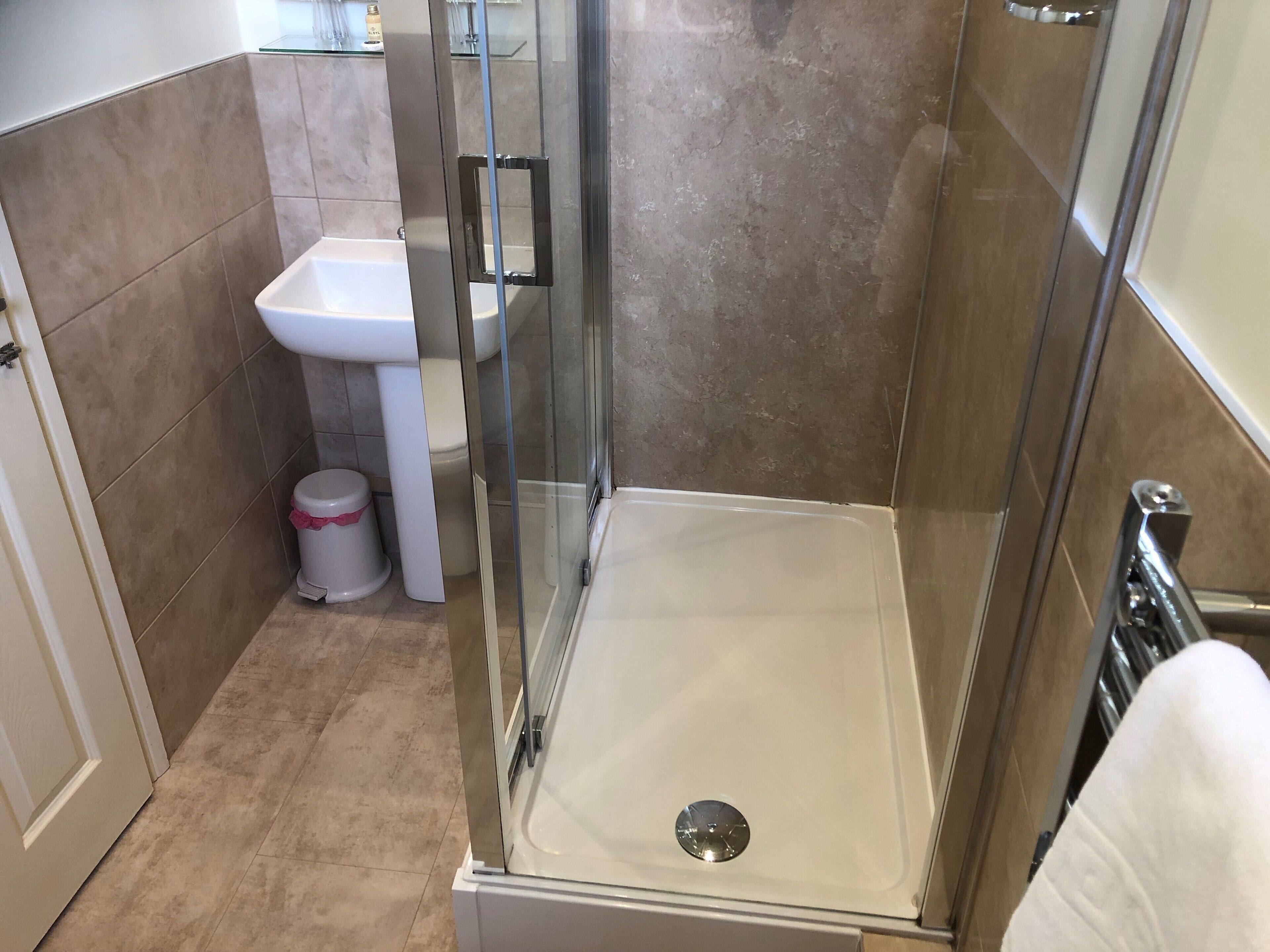 Un baño moderno con cabina de ducha de vidrio, un lavabo blanco y un inodoro.
