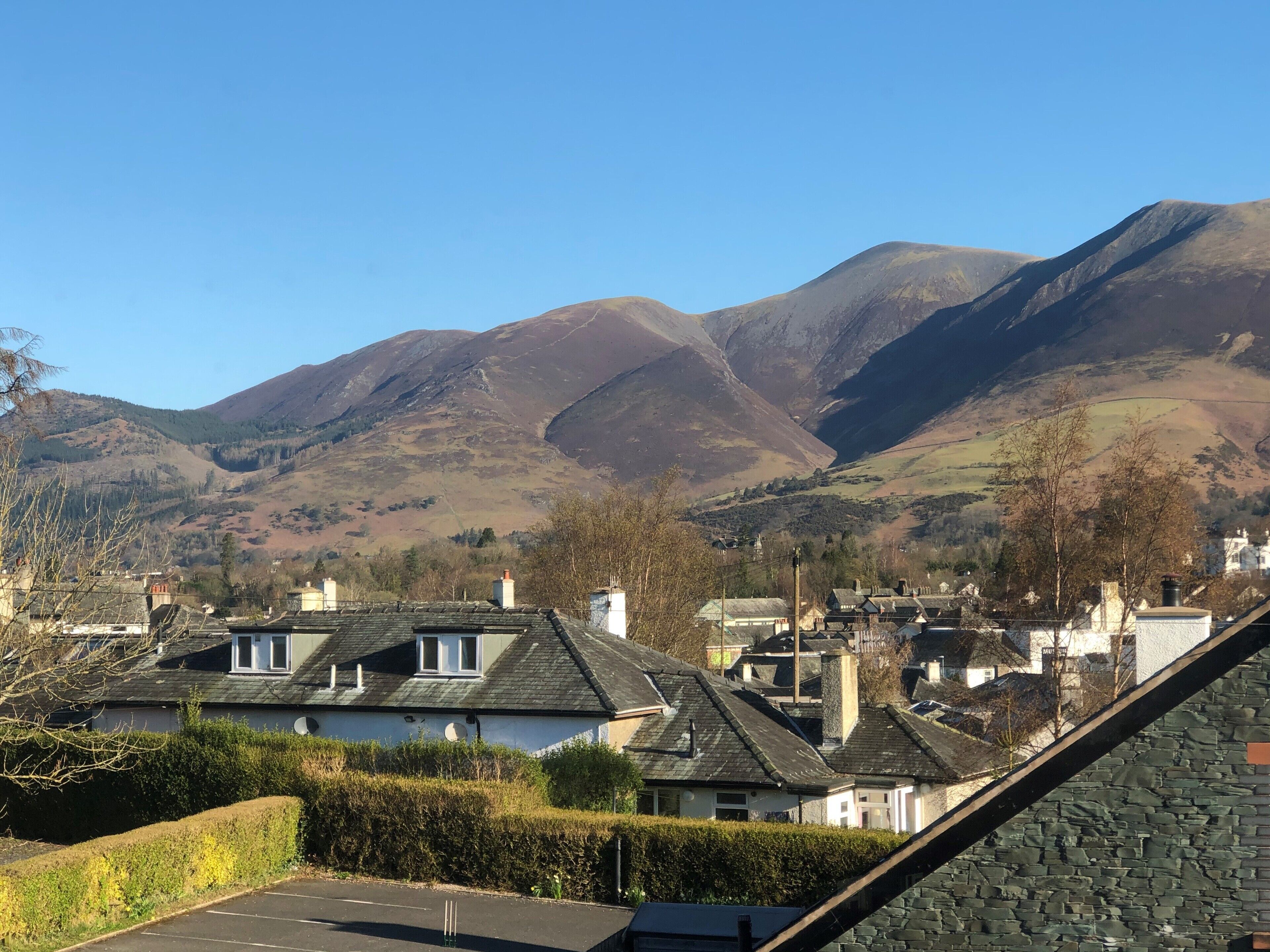 A residential area with houses, a parking lot, and mountains in the background.