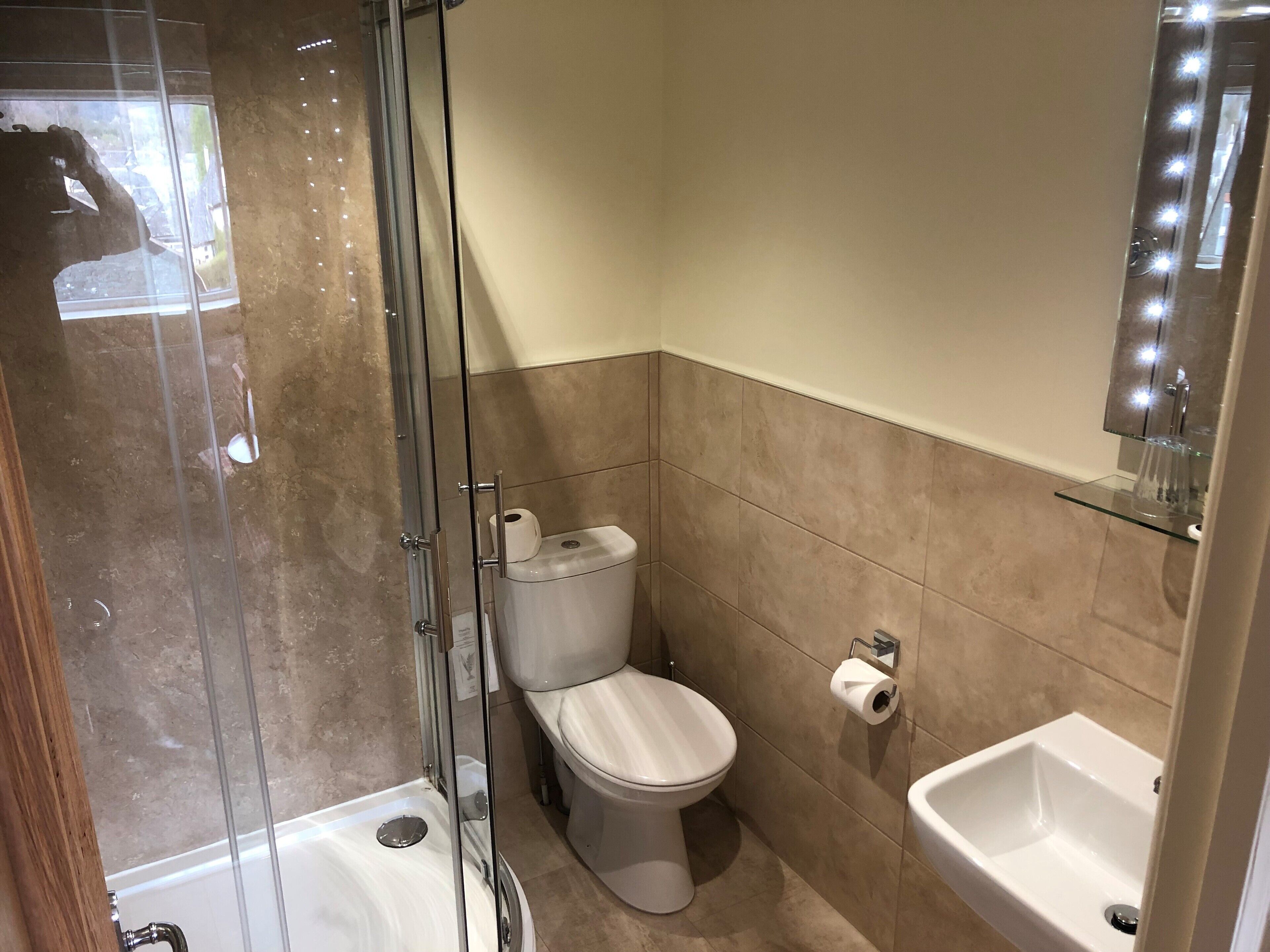 A bathroom with a glass-enclosed shower, a toilet, and a sink.