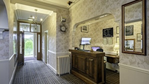 A reception area with a check-in counter, a computer, a clock, and a wall-mounted menu board.