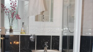 A bathroom with a toilet, sink, and glass-enclosed shower. - Tarn Hows Guest House (Keswick)