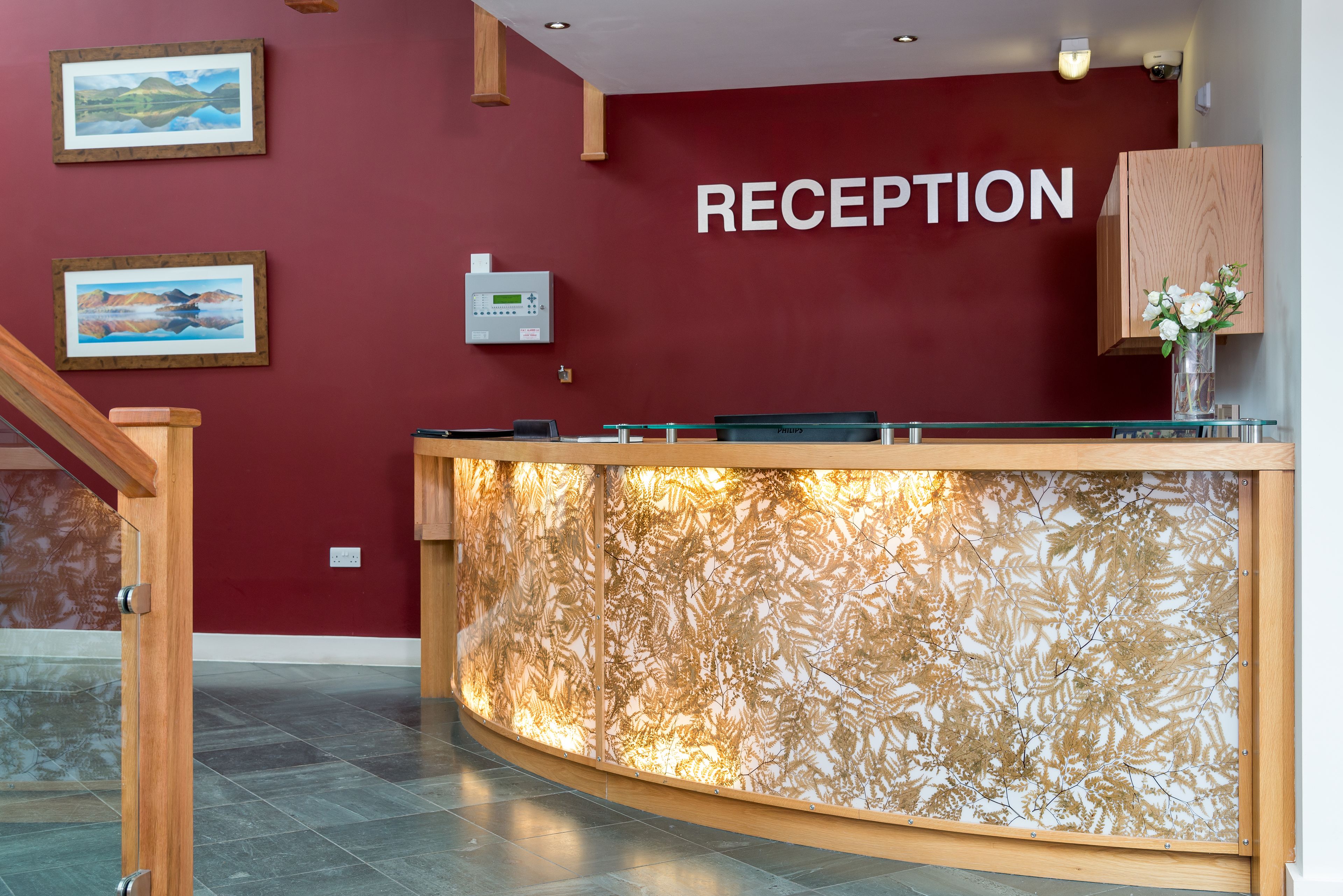 A reception area with a red wall, a reception desk, and framed artwork.