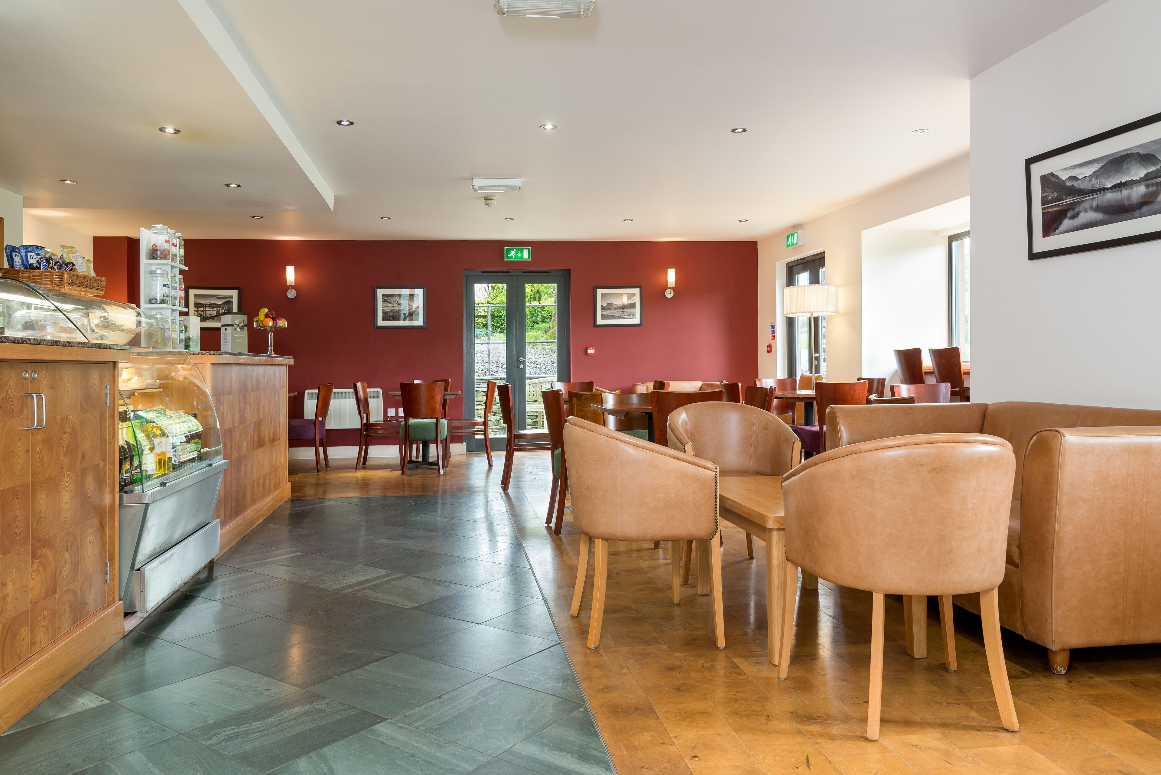 A modern hotel lobby with a reception desk, seating area, and a view of the outdoors.