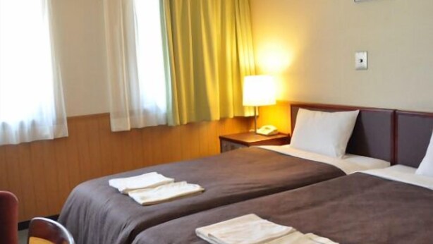 A hotel room with two beds, a nightstand with a lamp, and a window with curtains. - Hotel Select Inn Nagano (Nagano)