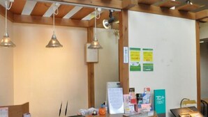 A reception desk with a wooden counter, hanging pendant lights, and a bulletin board with notices. - Hotel Select Inn Nagano (Nagano)