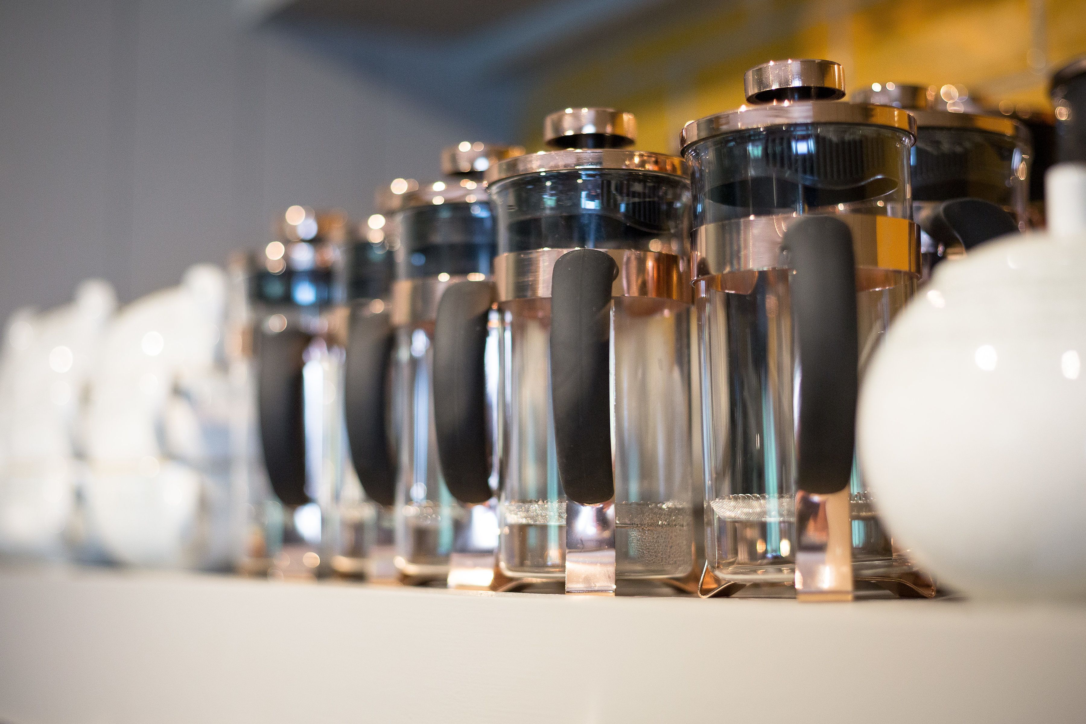 A row of clear glass bottles with black handles, likely containing beverages, arranged on a shelf.