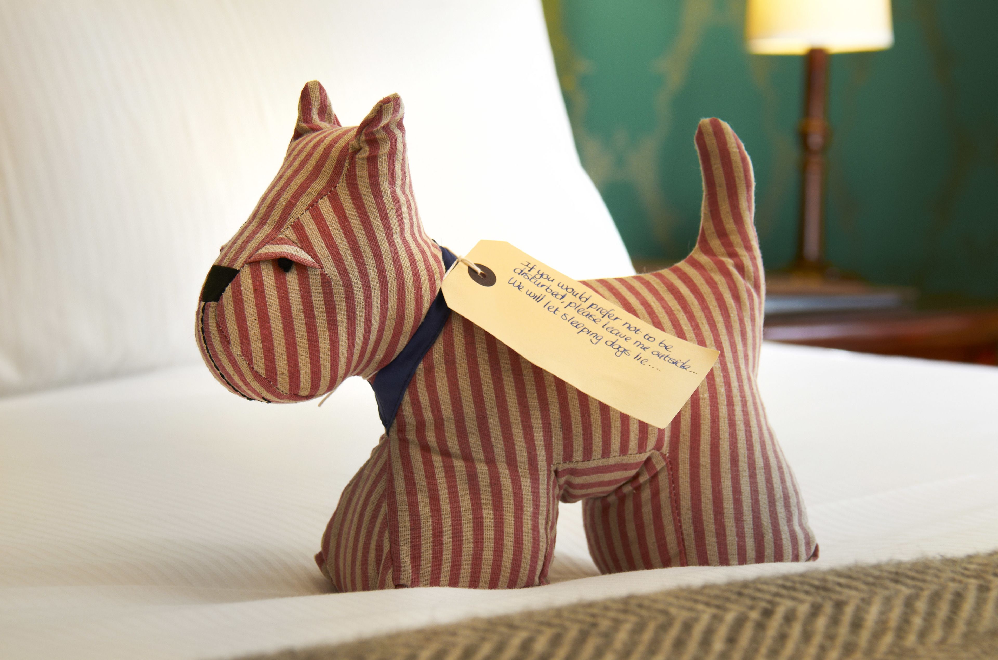 A striped dog figurine on a bed with a tag.