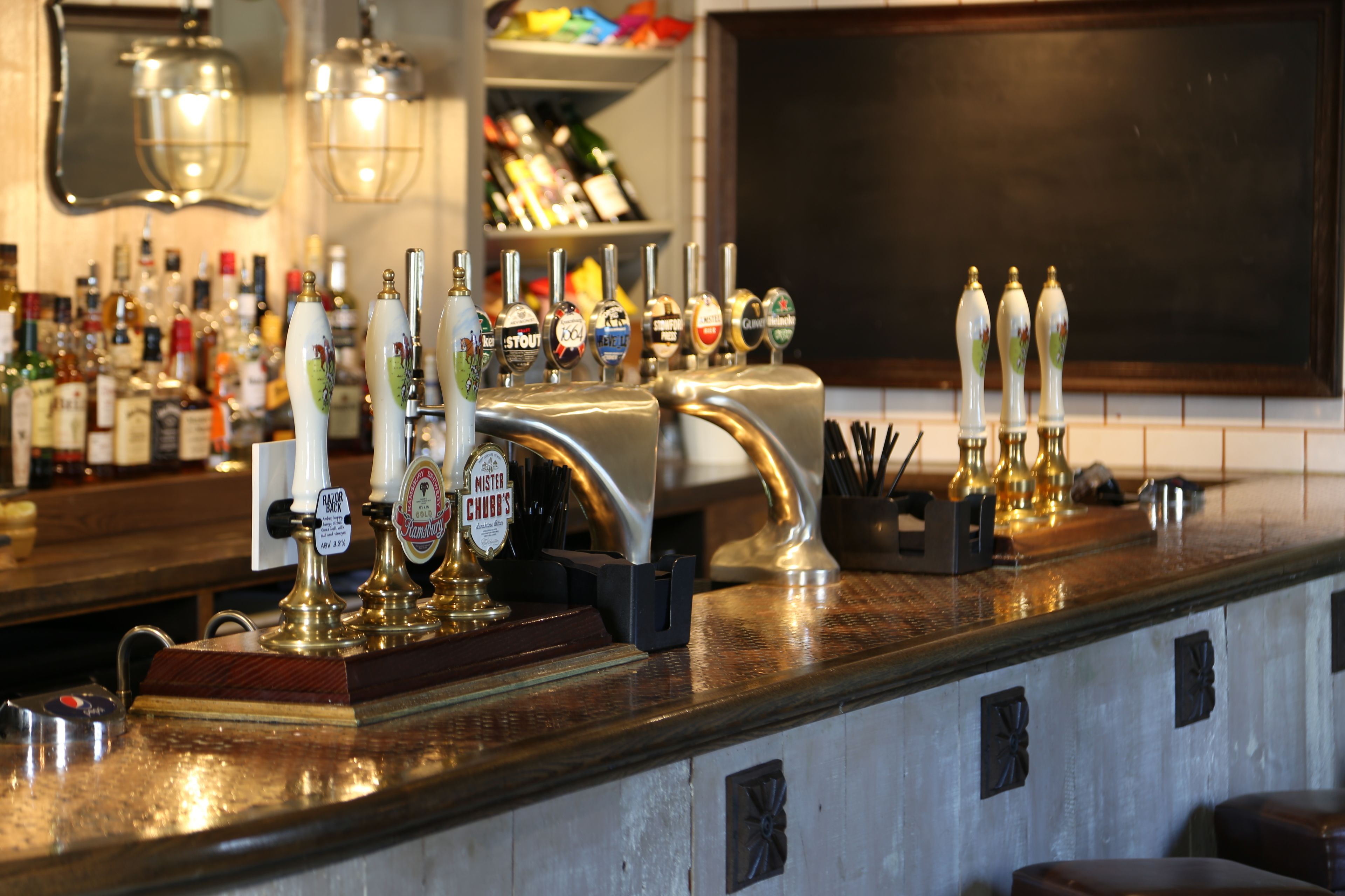 Eine Bar mit mehreren Zapfhähnen und einer Auswahl an Spirituosenflaschen im Hintergrund.