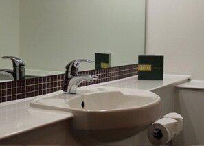 A bathroom with a sink, two faucets, and a mirror. - The Villa Express (Preston)