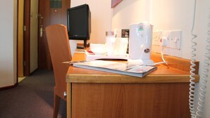 Ein Holztisch mit einem Computermonitor, einem weißen Telefon und einer Zeitschrift.