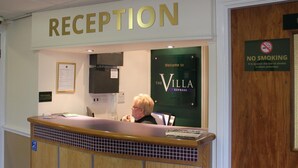 Ein Empfangsbereich mit einem Schild mit der Aufschrift 'RECEPTION', einem Schild 'NICHTRAUCHER' und einem Schild 'Welcome to The Villa Express'.