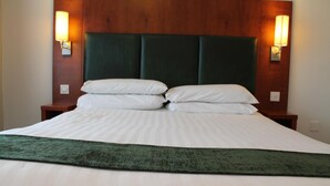 Ein Hotelzimmer mit einem großen Bett, zwei Nachttischen und Wandlampen.
