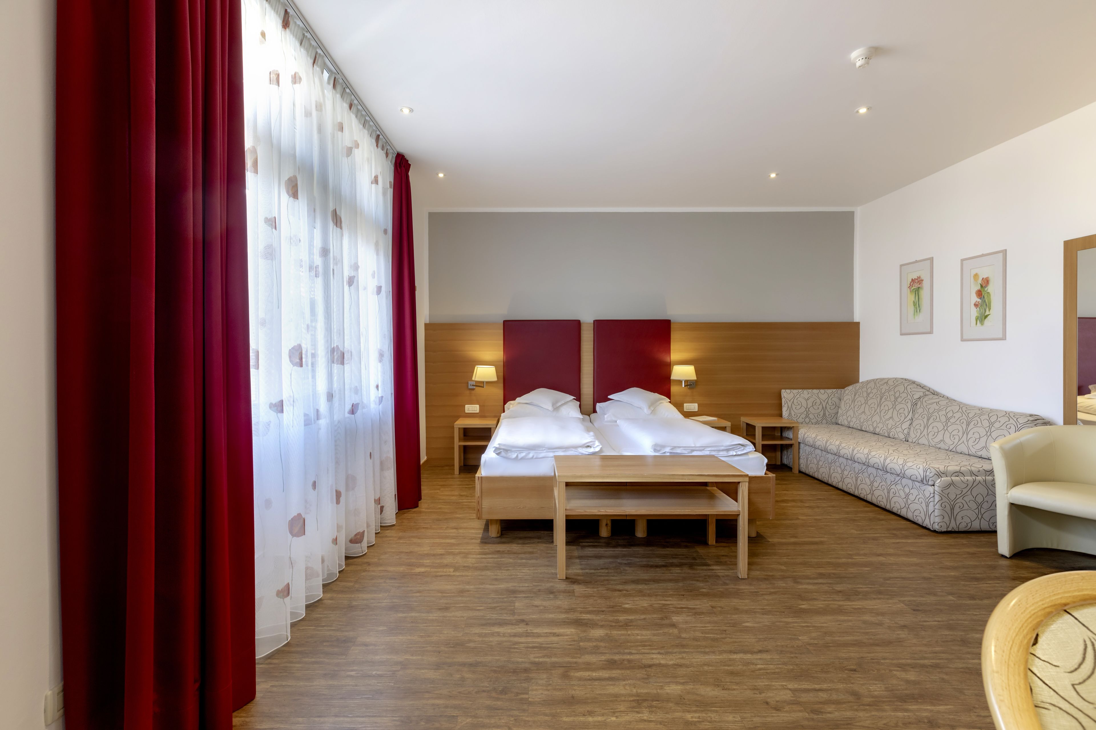 A hotel room with a bed, a sofa, a wooden table, and a chair.