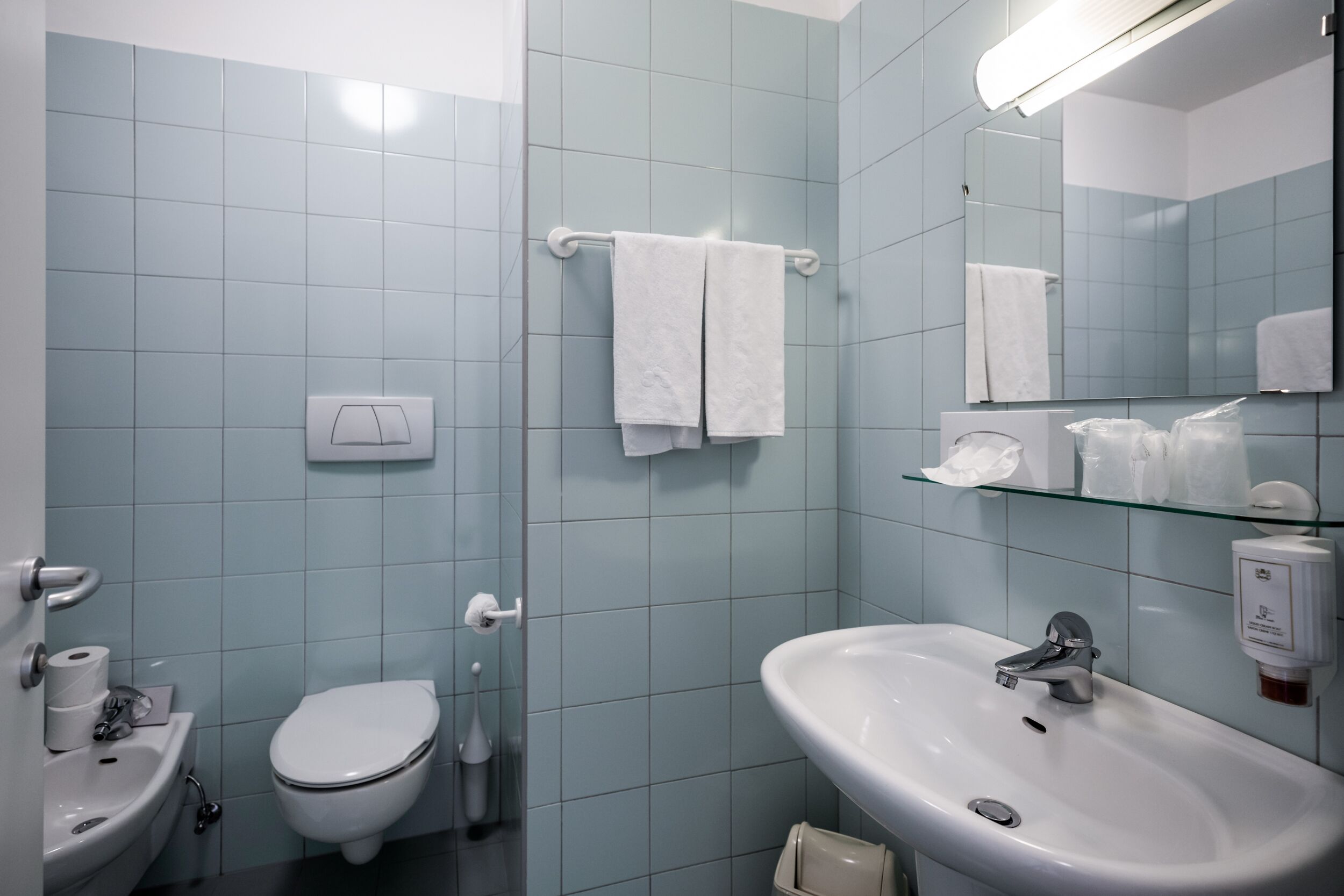 Baño con lavamanos blanco, inodoro y cabina de ducha de cristal.