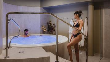 Un espace de détente avec un jacuzzi, une rambarde en métal et une personne debout près du jacuzzi.