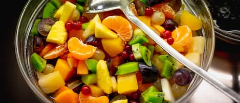 Un tazón de ensalada de frutas variadas con una cuchara.