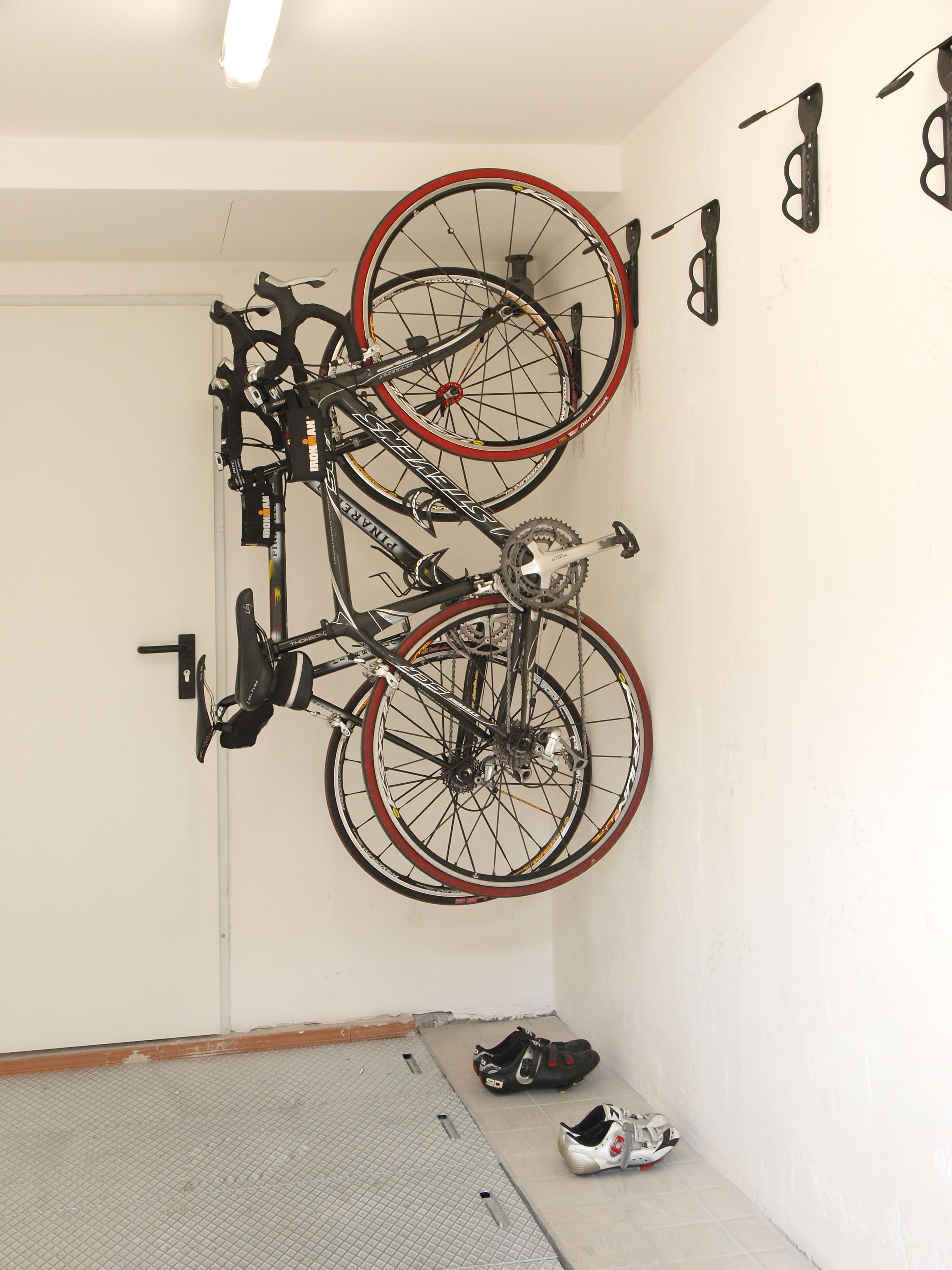 A bicycle mounted on a wall in a room with a tiled floor and a door.