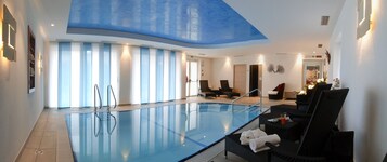 Una piscina techada, sillones reclinables de piscina