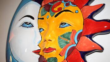 A colorful ceramic sculpture with abstract floral patterns and a sun motif.