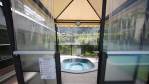 A hot tub under a covered area with a clock above it. - Hotel Miorelli (Nago-Torbole)
