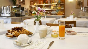 A breakfast setting with a variety of food items, including pastries, a glass of orange juice, and a coffee cup. - Hotel Miorelli (Nago-Torbole)