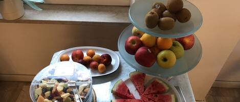 Une présentation de fruits comprenant des pommes, des oranges, des kiwis et des tranches de pastèque, disposés sur une table.