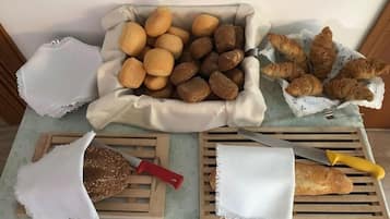 Variedad de panes y pasteles sobre una mesa, junto a un cuchillo y tabla de cortar.