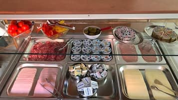 Un bufé con diversos alimentos, incluyendo carnes, quesos y salsas.
