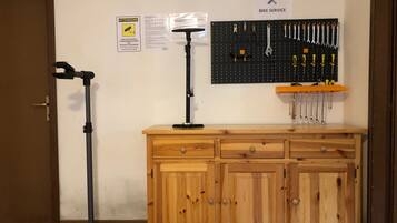 A workshop area with a pegboard wall displaying tools, a wooden cabinet with drawers, and a tripod stand.