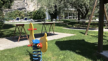 Un patio de juegos con un sube y baja, columpios y una mesa.