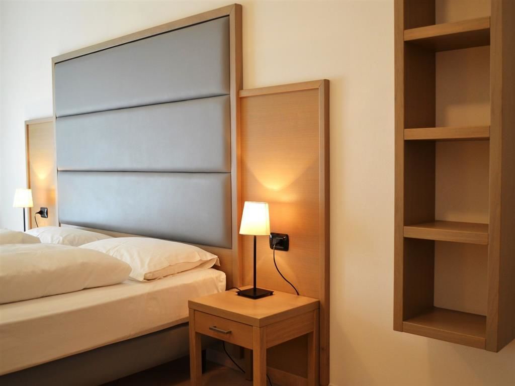 Une chambre d’hôtel comprenant un lit, des tables de chevet et une étagère intégrée.
