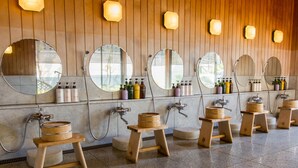 A row of wooden stools with wooden barrels, a mirror, and a wall-mounted shelf with toiletries. - Hotel Hagoromo (Shizuoka)