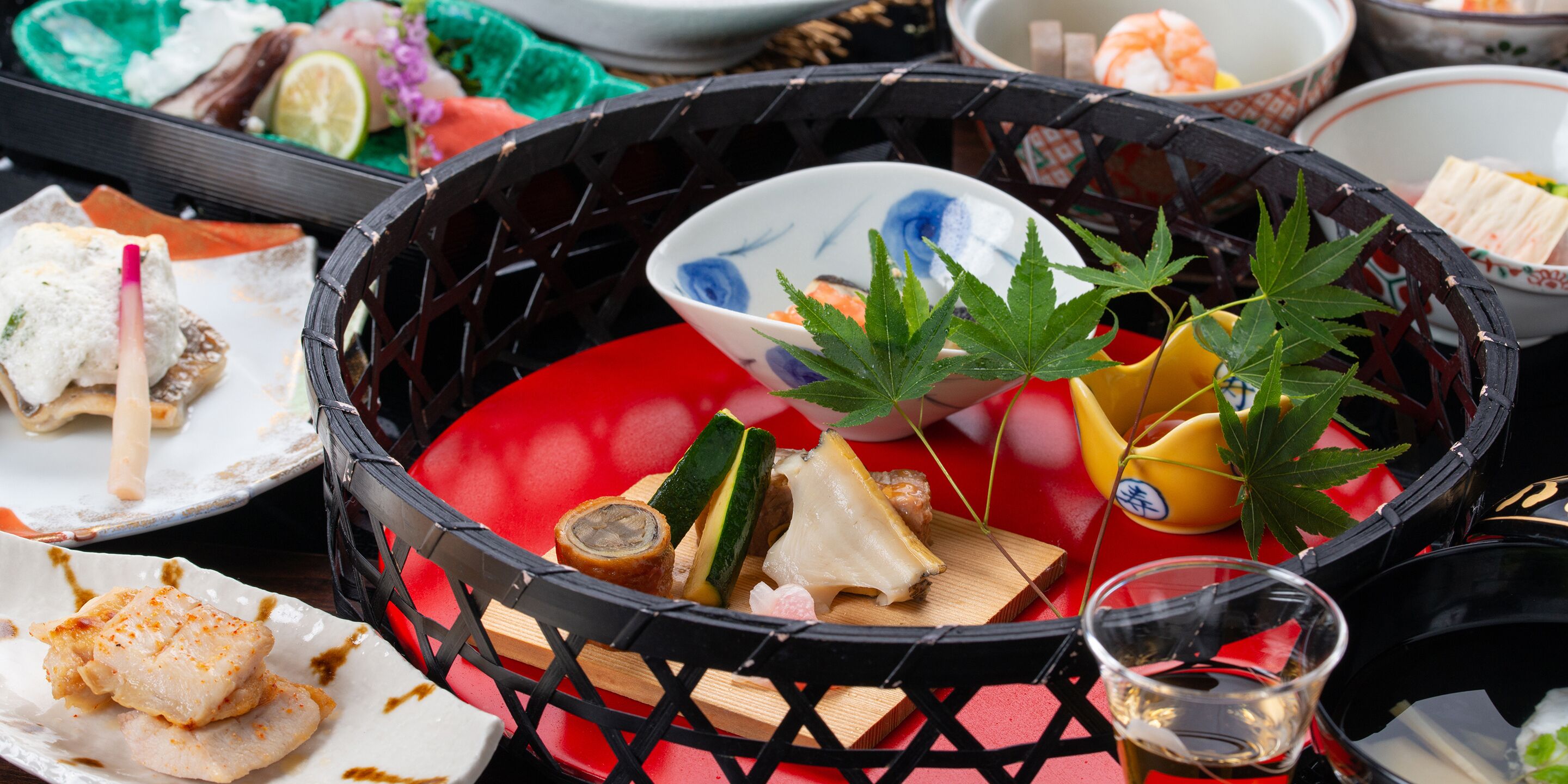A traditional Japanese meal setup with various dishes and a small glass of sake.