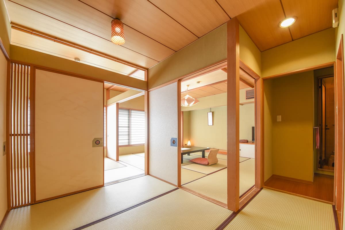 Ein traditioneller japanischer Raum mit Tatami-Boden, Schiebetüren und niedriger Decke mit eingelassener Beleuchtung.